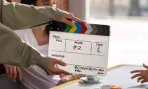 an amateur crew member holding a clapperboard in front of actors